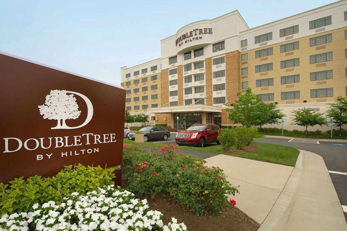 A DoubleTree by Hilton hotel with a sign, a parking lot, and a building facade.
