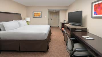 A hotel room with a large bed, a desk with a computer, a television, and a chair.