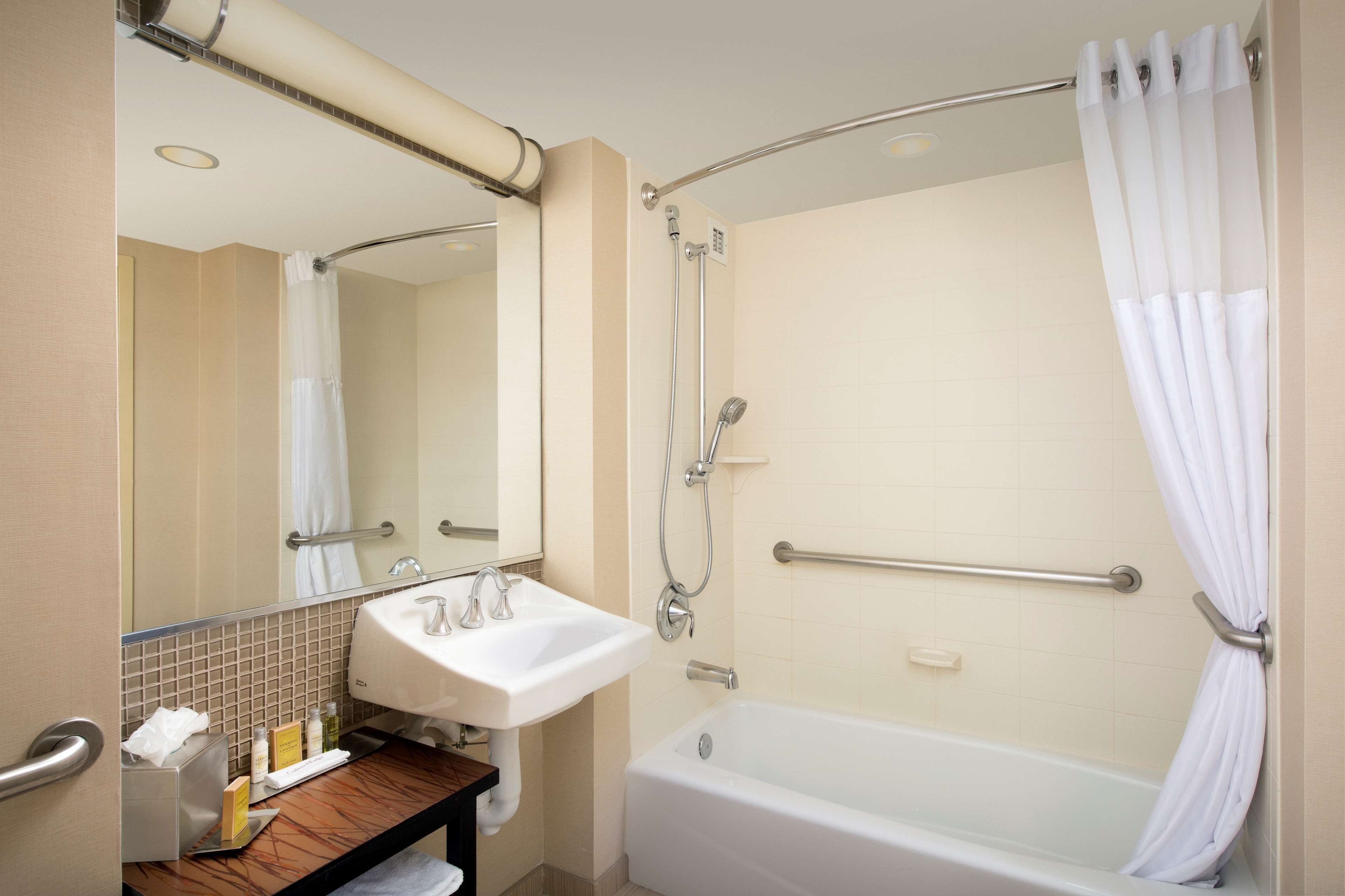 A bathroom with a sink, mirror, shower, and bathtub.