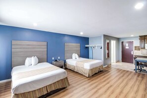 A hotel room with two beds, a desk, and a bathroom.