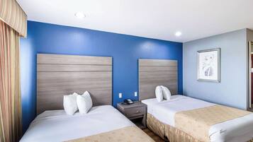 A hotel room with two beds, a nightstand, a telephone, and a framed picture on the wall.