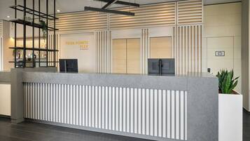 Un mostrador de recepción de diseño moderno, con una encimera gris, listones verticales y un letrero que dice "FOUR POINTS FLEX".
