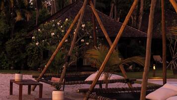 A beach setting with wooden structures, including a hammock and a small table with a candle.