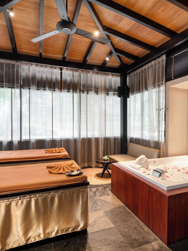 Relax in a serene spa room with a bathtub, massage tables, and a tranquil atmosphere.