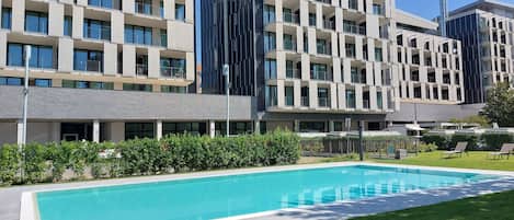 Een seizoensgebonden buitenzwembad en ligstoelen