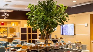 Un buffet proposant une variété de plats et agrémenté d’un grand arbre artificiel servant de pièce maîtresse.