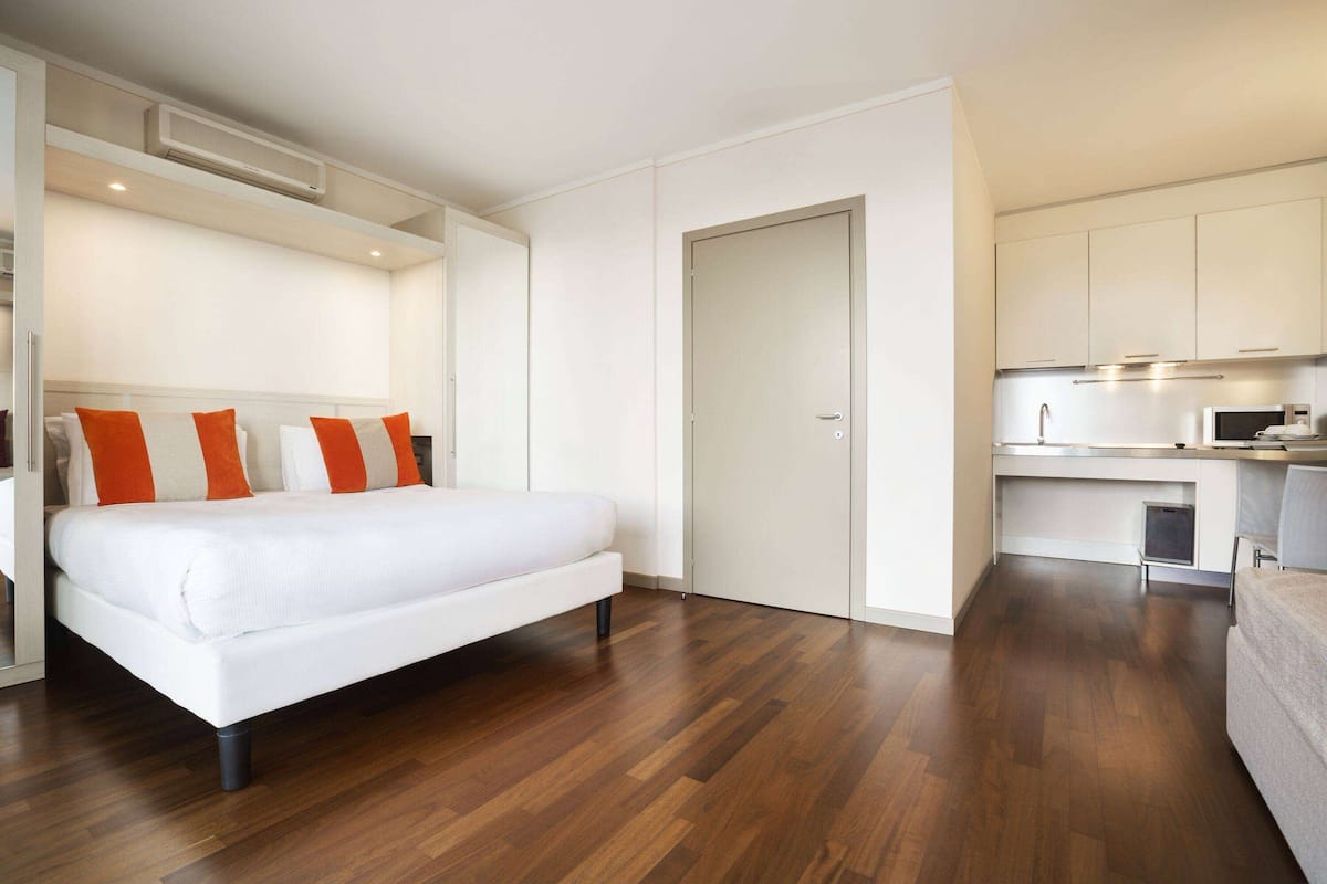 Una habitación de hotel moderna con una cama grande, kitchenette y un baño separado.