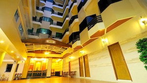 Interior de um hotel com vários níveis, varandas, átrio central e área de recepção.