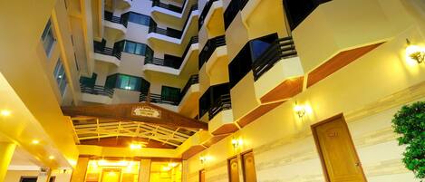 A multi-level hotel interior with balconies, a central atrium, and a reception area.