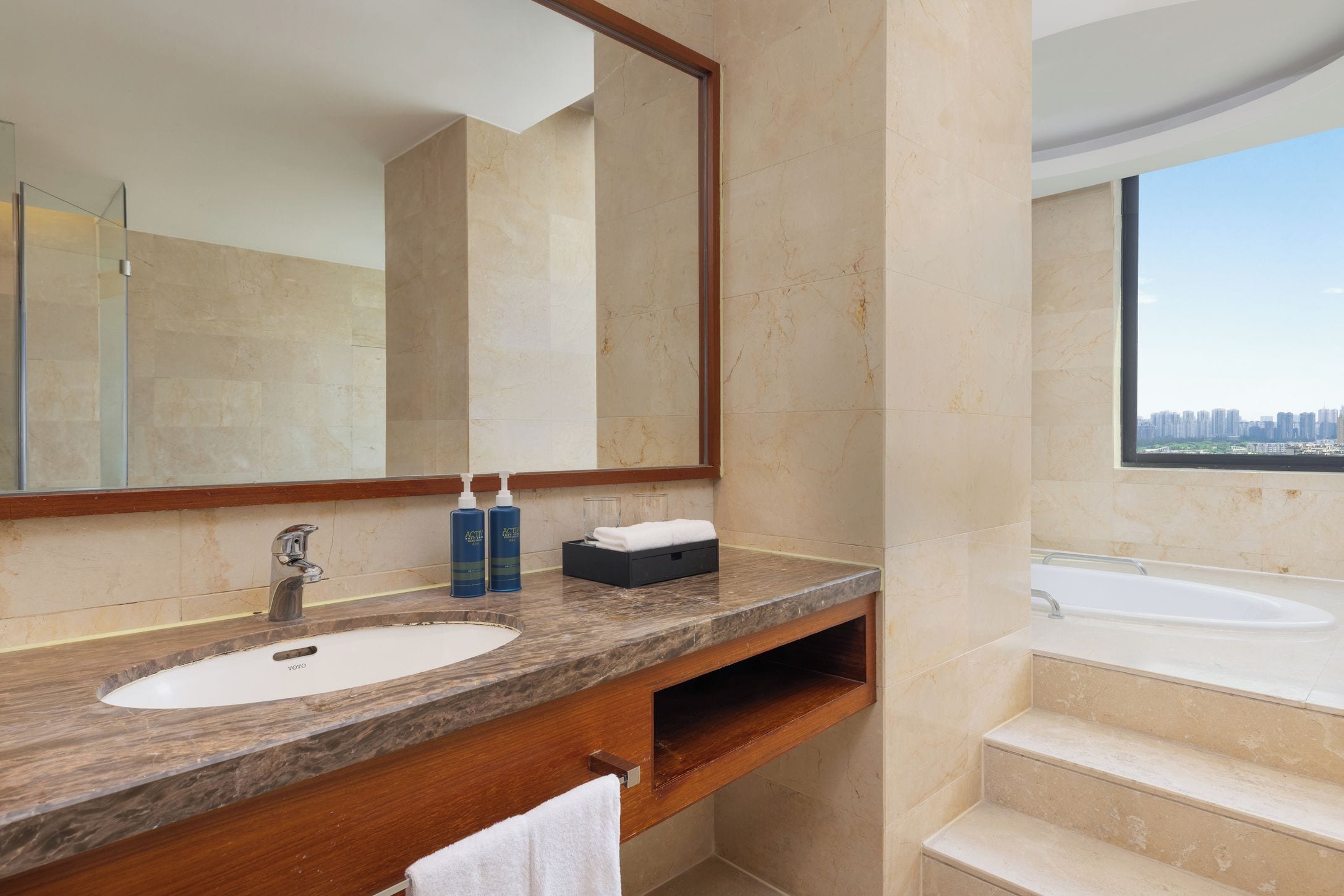 A bathroom with a marble vanity, a large mirror, a sink, and a bathtub.