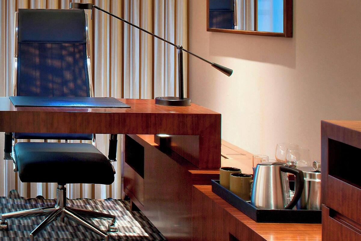 A hotel room with a desk, chair, and a coffee maker on a tray.