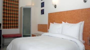 A hotel room with a large bed, a bench, a wardrobe, and a door.