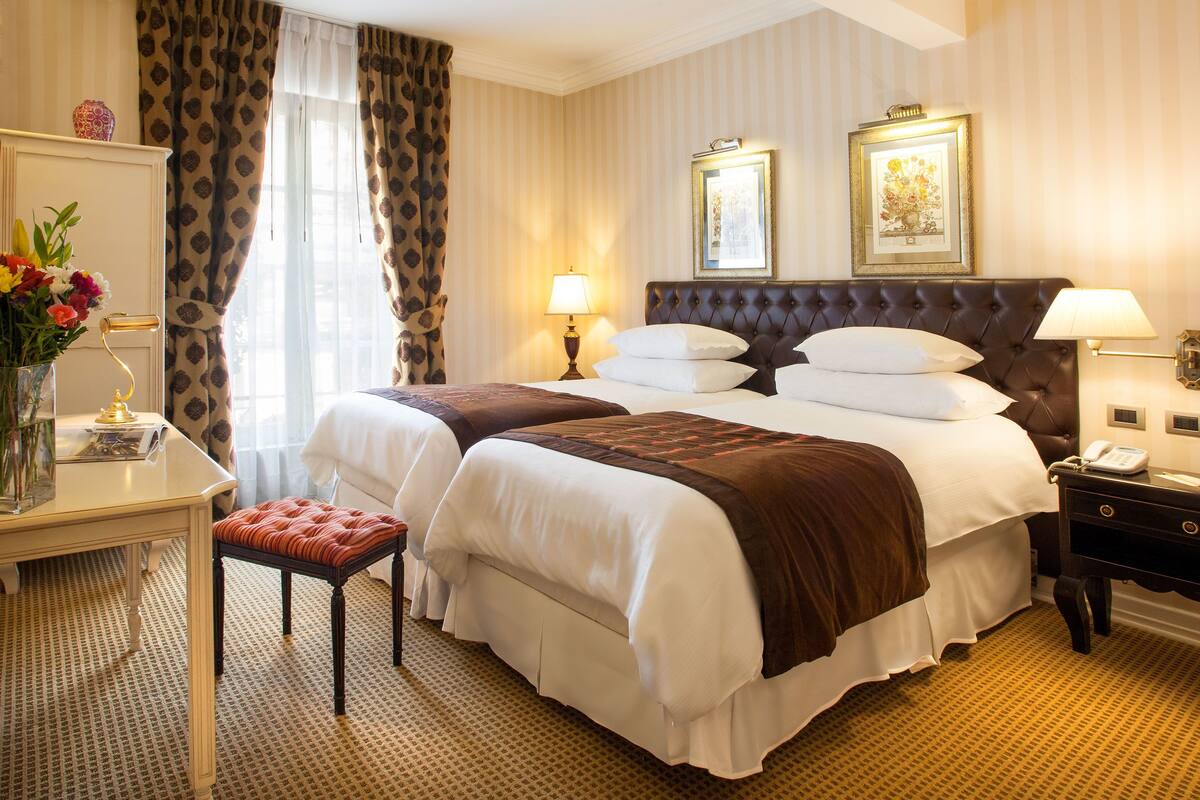 Een hotelkamer met een groot bed, twee nachtkastjes, een bureau en een stoel.