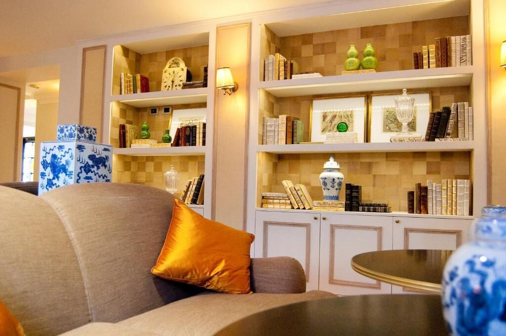 A living room with a sofa, a table, and a bookshelf filled with books and decorative items.
