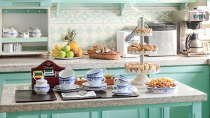 A kitchen counter with tea service, fruit, and pastries.