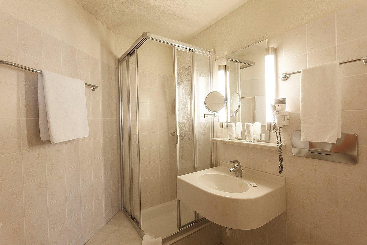 A modern bathroom with a glass-enclosed shower, a sink, and a mirror.