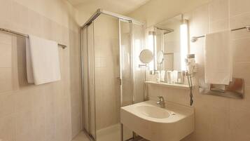 A modern bathroom with a glass-enclosed shower, a sink, and a mirror.