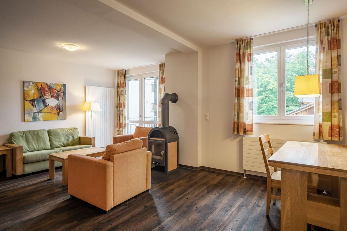 Ein gemütliches Wohnzimmer mit einer Couch, Sesseln, einem Tisch und einem Kamin.