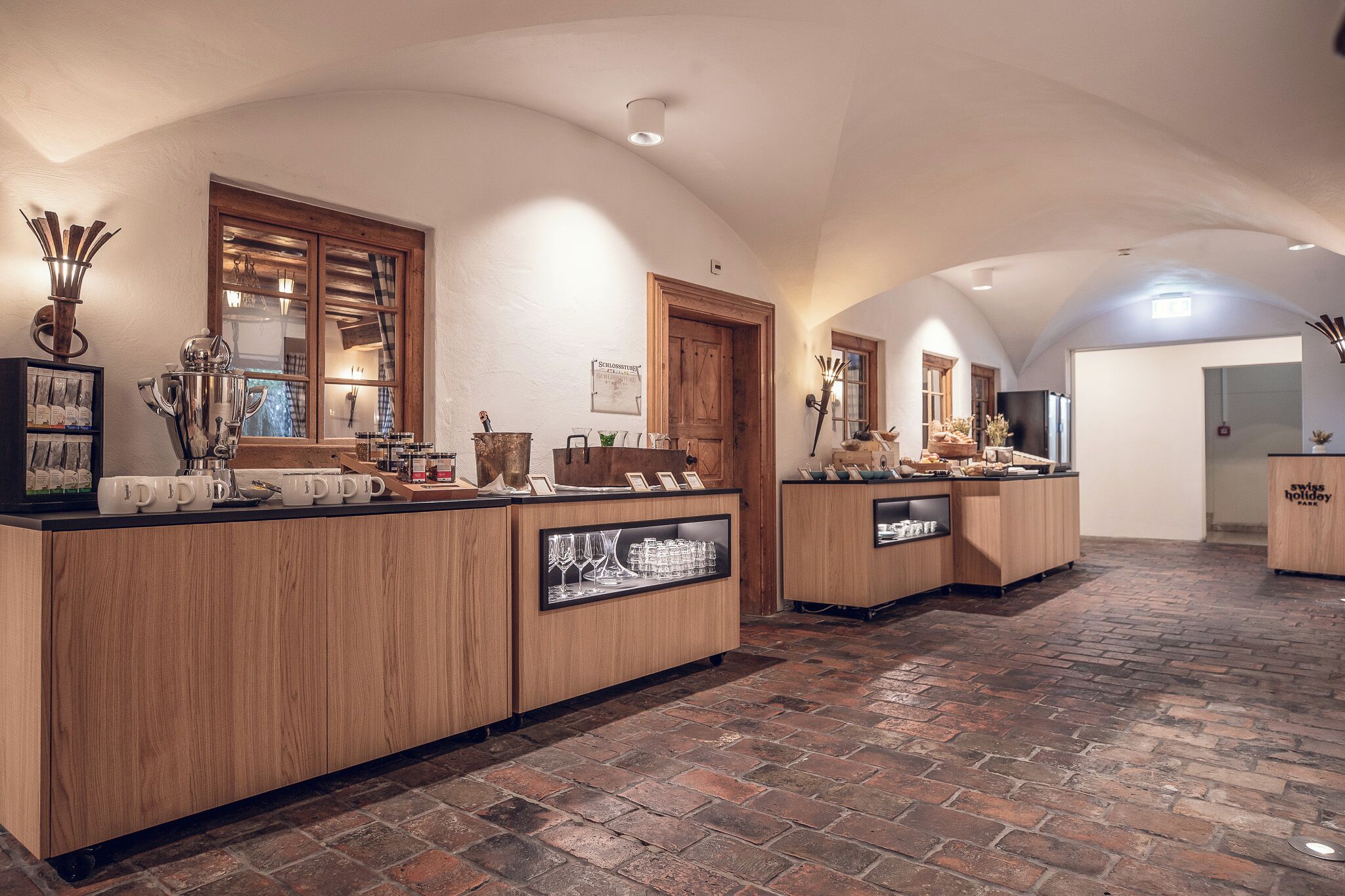 A reception area with wooden counters, glass display cases, and a brick floor.