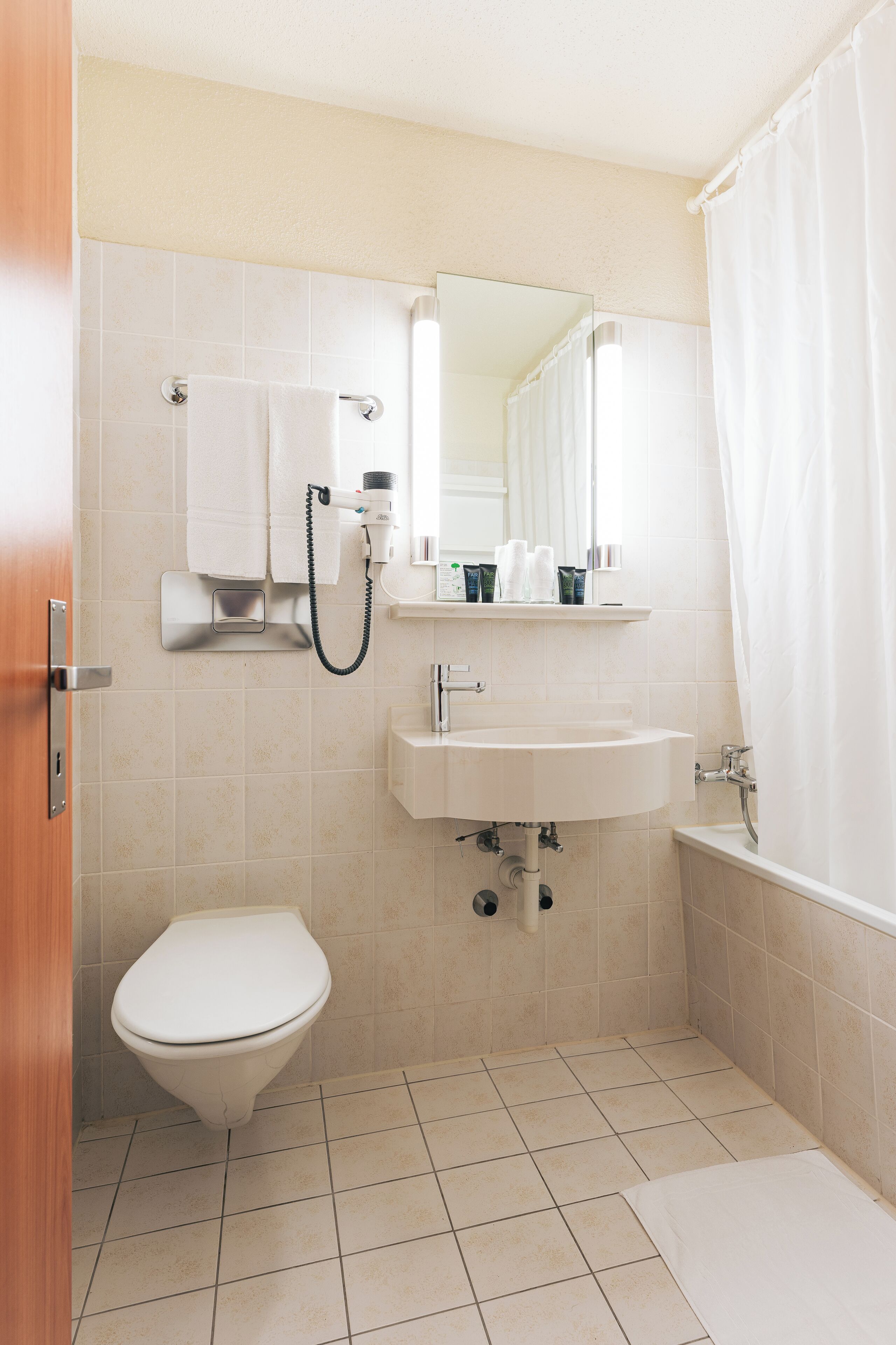 A small, clean bathroom with a toilet, sink, and shower.