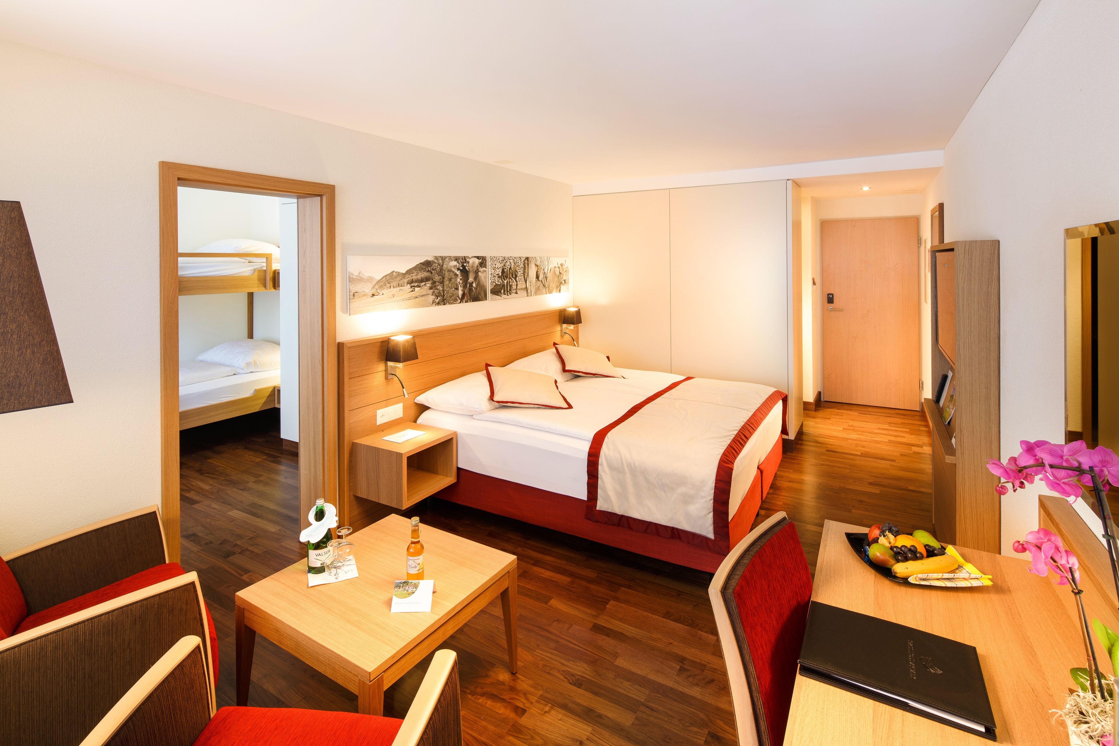 Ein Hotelzimmer mit Bett, Nachttisch, Lampe und Schreibtisch mit Stuhl.