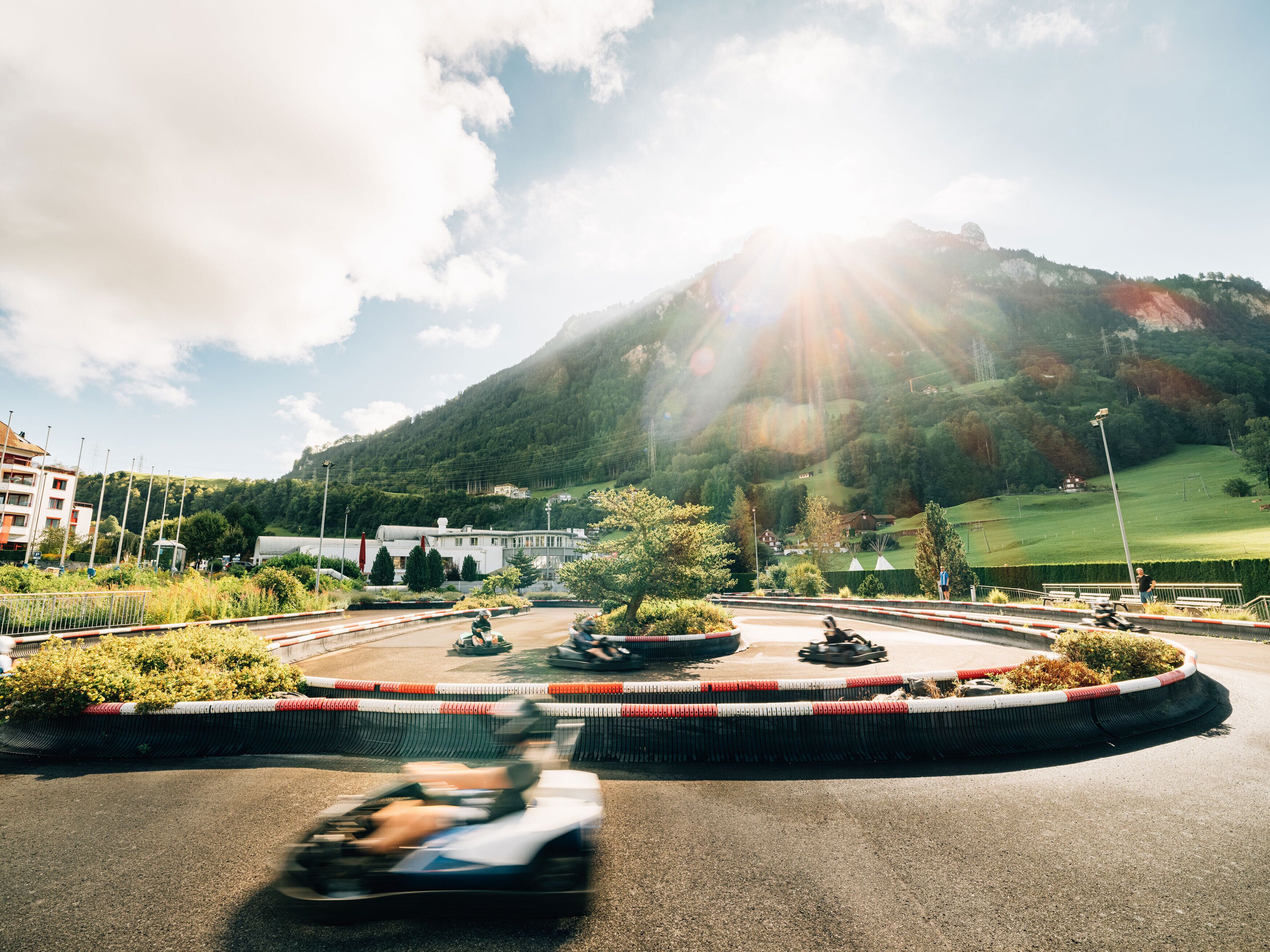 Ein Kreisel mit Go-Karts, umgeben von Grünflächen und einem Berg im Hintergrund.