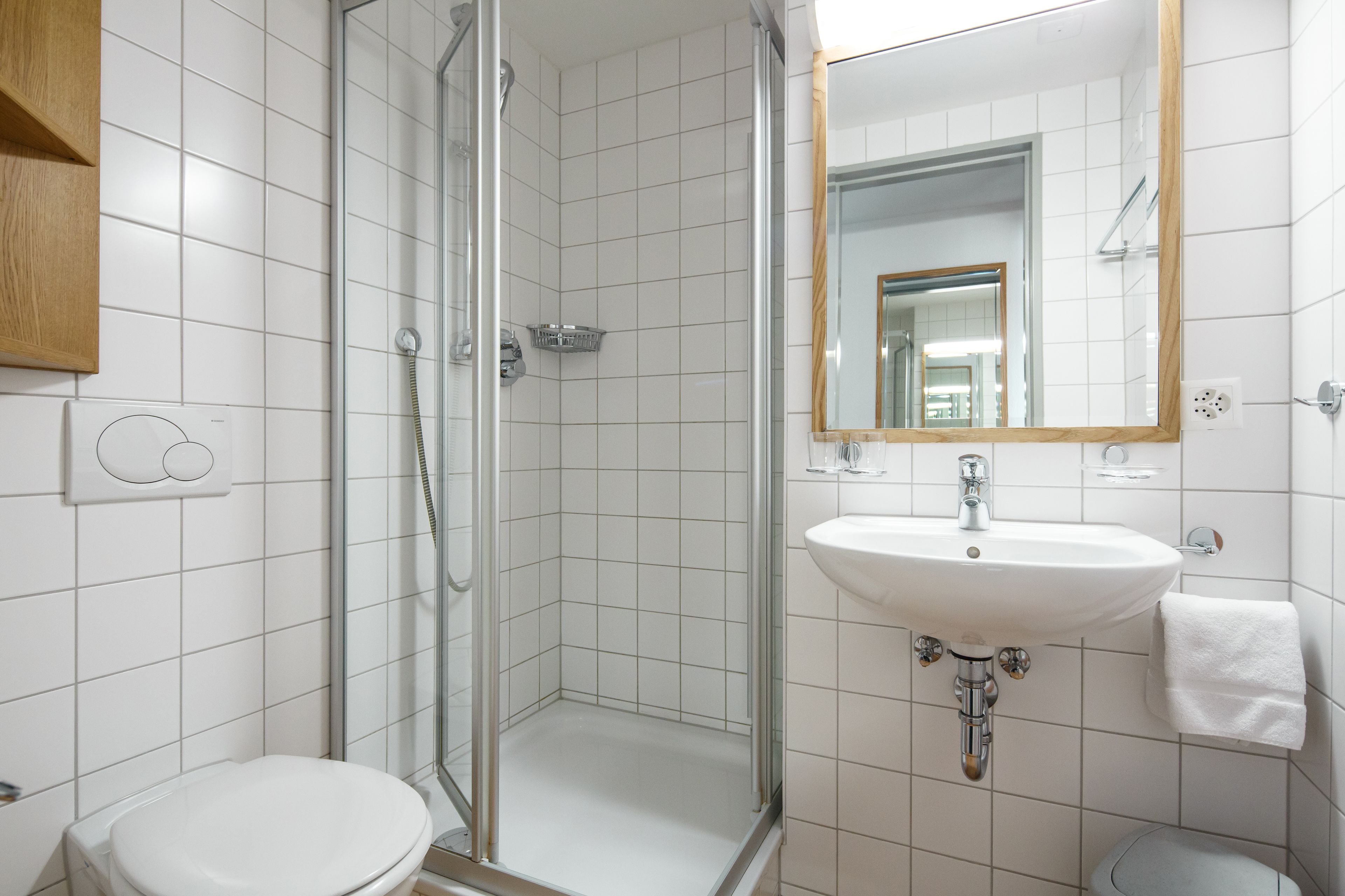 Un baño moderno con ducha de vidrio, lavamanos blanco y retrete.