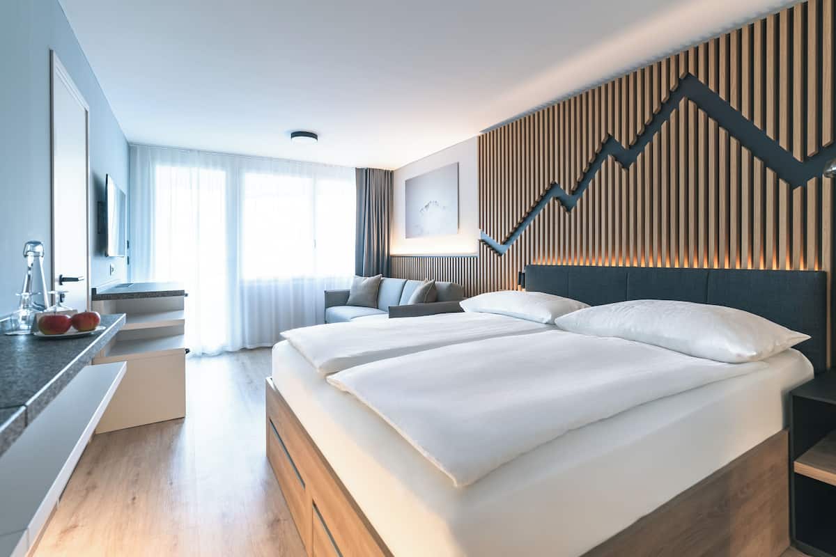 Ein modernes Hotelzimmer mit zwei Betten, einem Schreibtisch und einer Sitzecke.