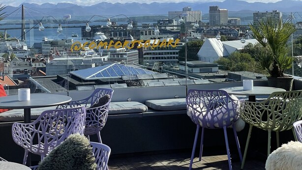 A rooftop terrace with outdoor seating, a view of a cityscape, and distant mountains. - Comfort Hotel Square (Stavanger)
