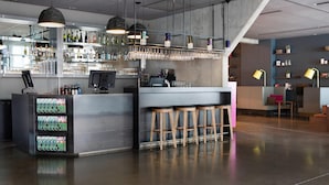 Zona de bar moderna con barra, taburetes y una variedad de botellas y vasos.