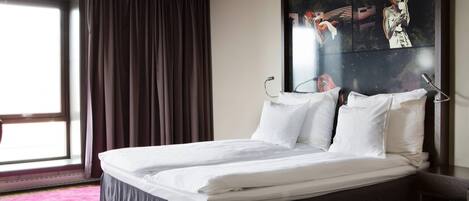 Habitación de hotel con una cama grande, una ventana con cortinas y un cuadro en la pared.