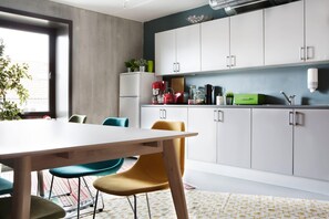 A modern kitchen with white cabinets, a dining table, and colorful chairs. - Comfort Hotel Square (Stavanger)