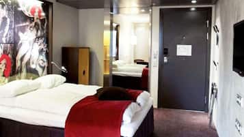 Una habitación de hotel con una cama, un espejo, una puerta y un televisor montado en la pared.