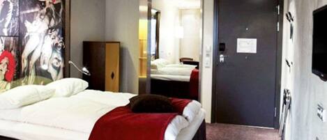 Una habitación de hotel con una cama, un espejo, una puerta y un televisor montado en la pared.