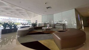 A modern lobby with a curved seating area, a round coffee table, and potted plants. - Days Inn Guangzhou (Guangzhou)