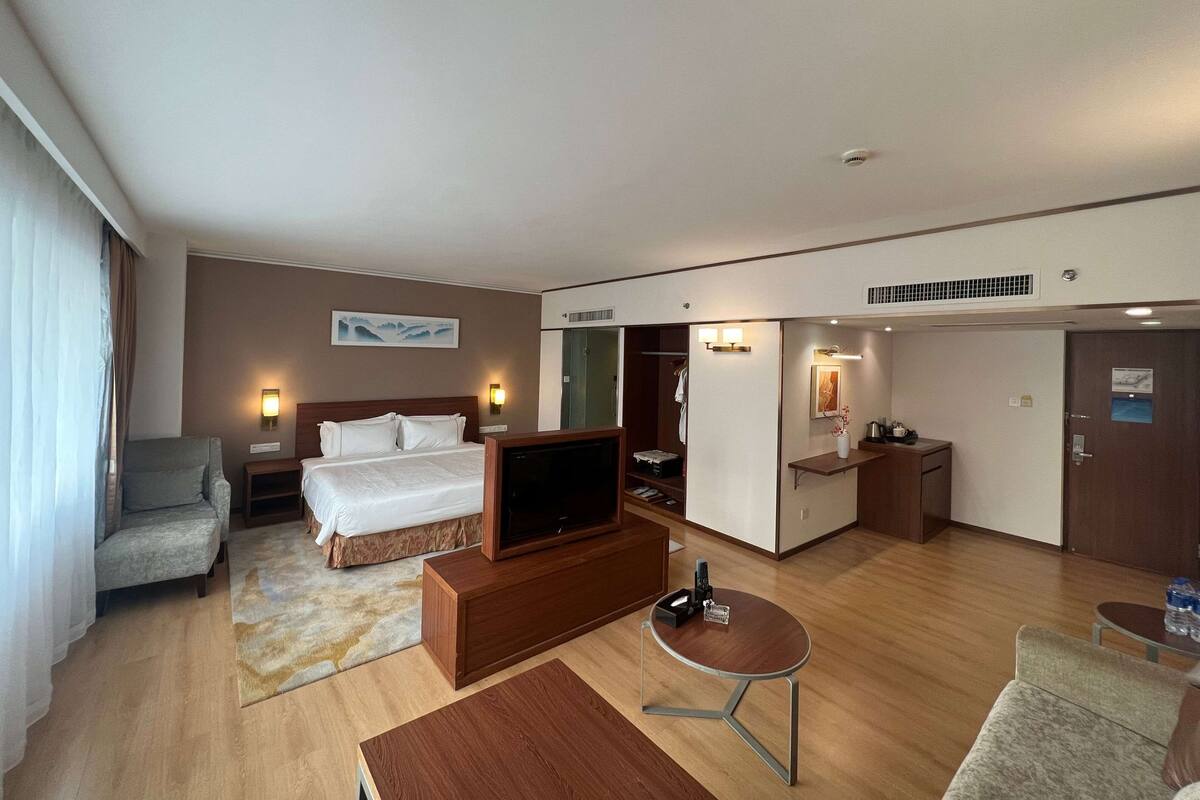 A hotel room with a bed, a TV, a desk, a chair, and a small table.