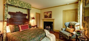 A traditional bedroom with a four-poster bed, a fireplace, a chair, and a nightstand. - Inn by the bandstand a Boutique Hotel (Exeter)