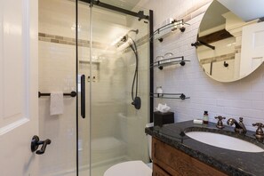 A modern bathroom with a glass-enclosed shower, a wooden vanity with a marble countertop, and a large mirror above the sink. - Inn by the bandstand a Boutique Hotel (Exeter)