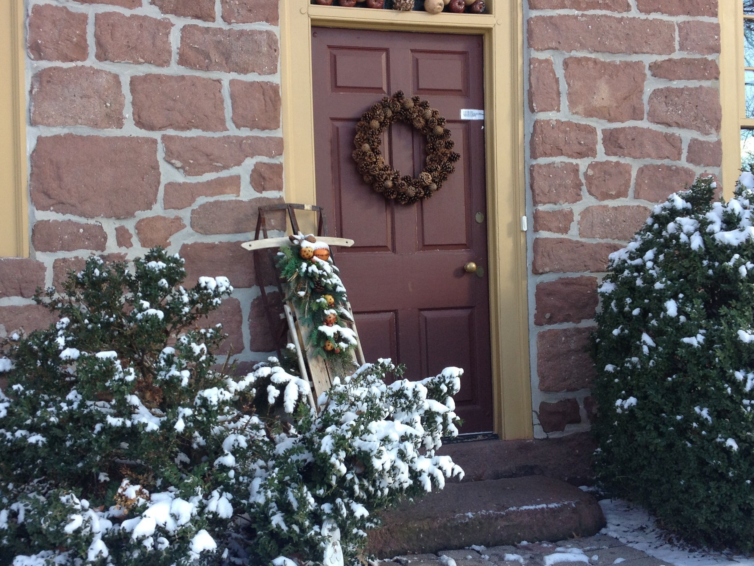Un bâtiment en pierre avec une porte marron, une guirlande et une échelle décorée.