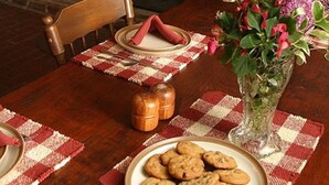 Un coin repas chaleureux avec une cheminée en briques, une table en bois et une assiette de biscuits.