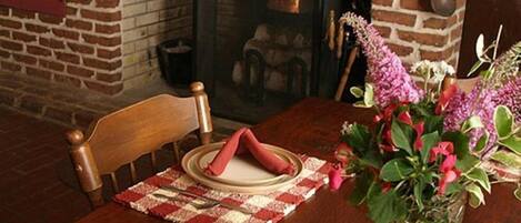 Un rincón comedor acogedor con chimenea de ladrillo, una mesa de madera y un plato de galletas.