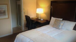 A hotel room with a large bed, a desk with a lamp, and a chair. - Wayne Inn (Honesdale)