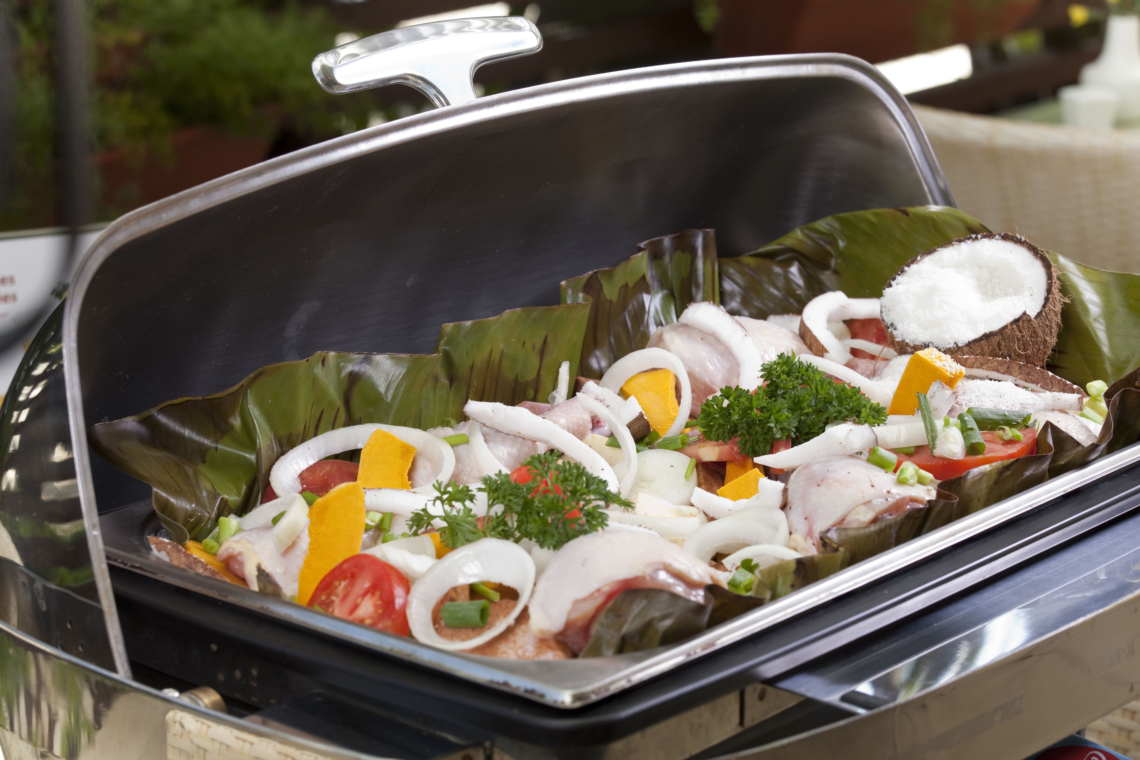 Un buffet proposant une variété d’aliments, notamment des viandes, des légumes et des accompagnements, servis sur un plateau avec un couvercle.
