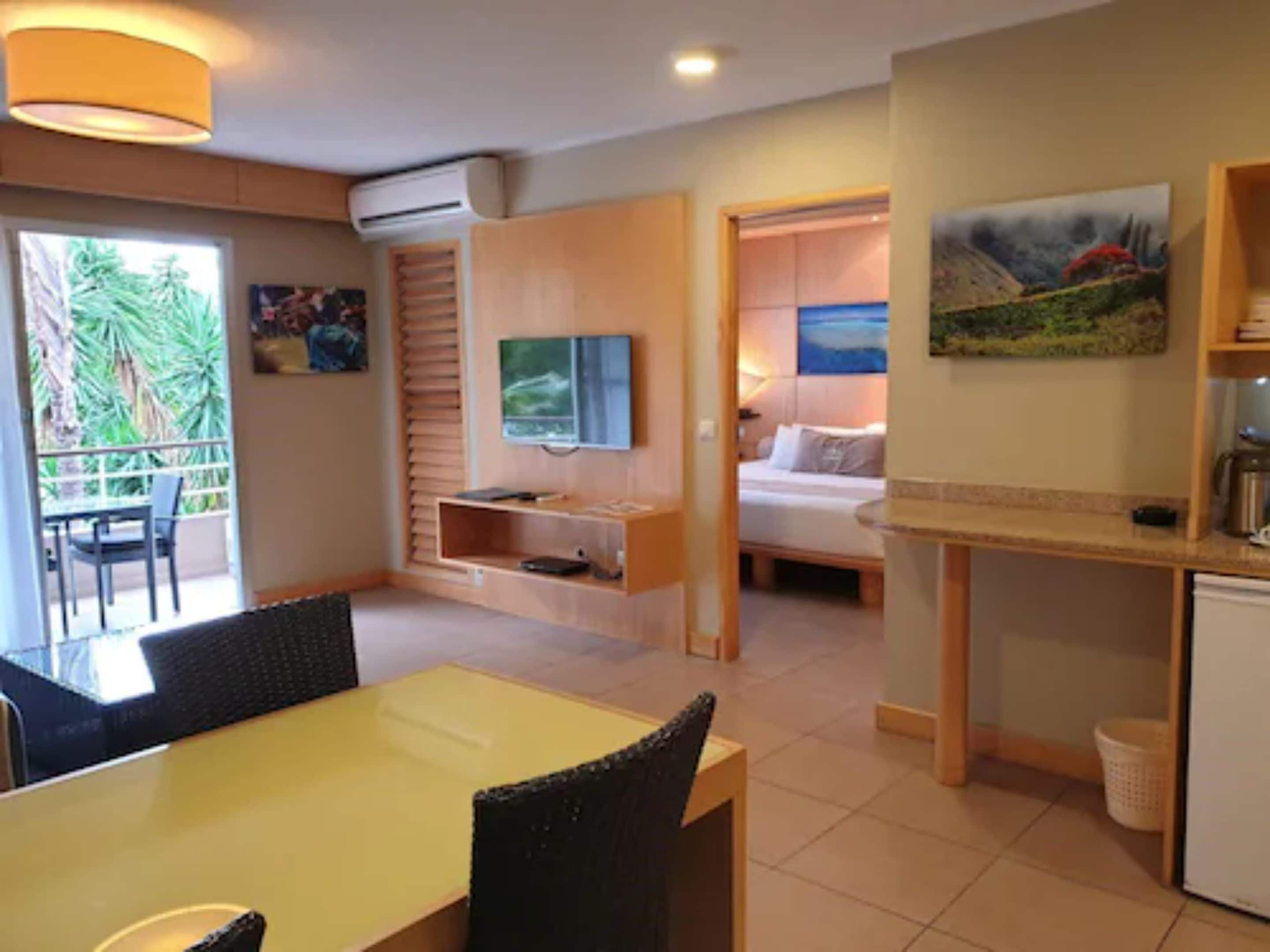 Een hotelkamer met een eethoek, een bed, een televisie en een schilderij.