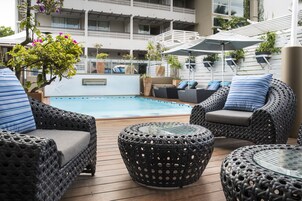 Una piscina al aire libre, sombrillas, sillones reclinables de piscina