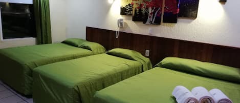 Een hotelkamer met twee enkele bedden, een houten hoofdbord, een telefoon aan de muur en drie schilderijen.