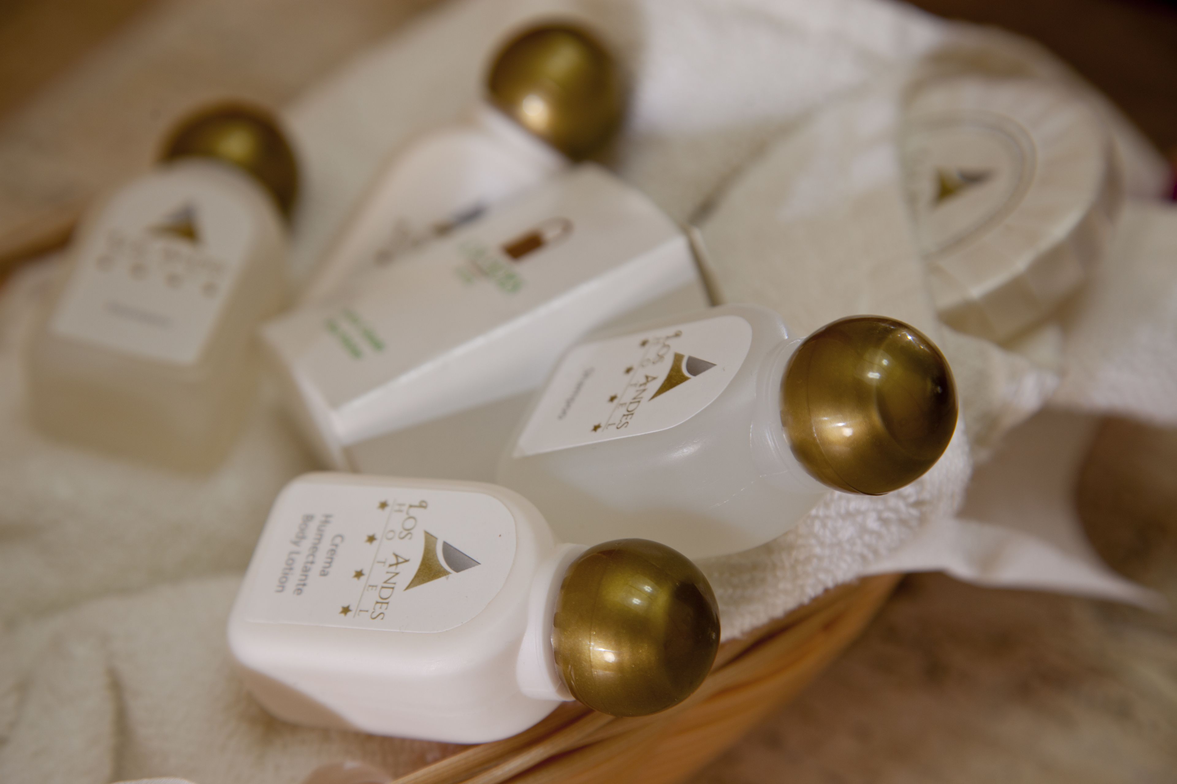 A collection of white bottles with gold caps, likely containing toiletries, arranged on a white towel.