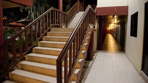 A staircase with wooden railings leading to a covered area with a view of palm trees. - Hotel Los Andes (Coatzacoalcos)