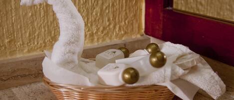 A wicker basket with toiletries and a white towel on a marble floor.