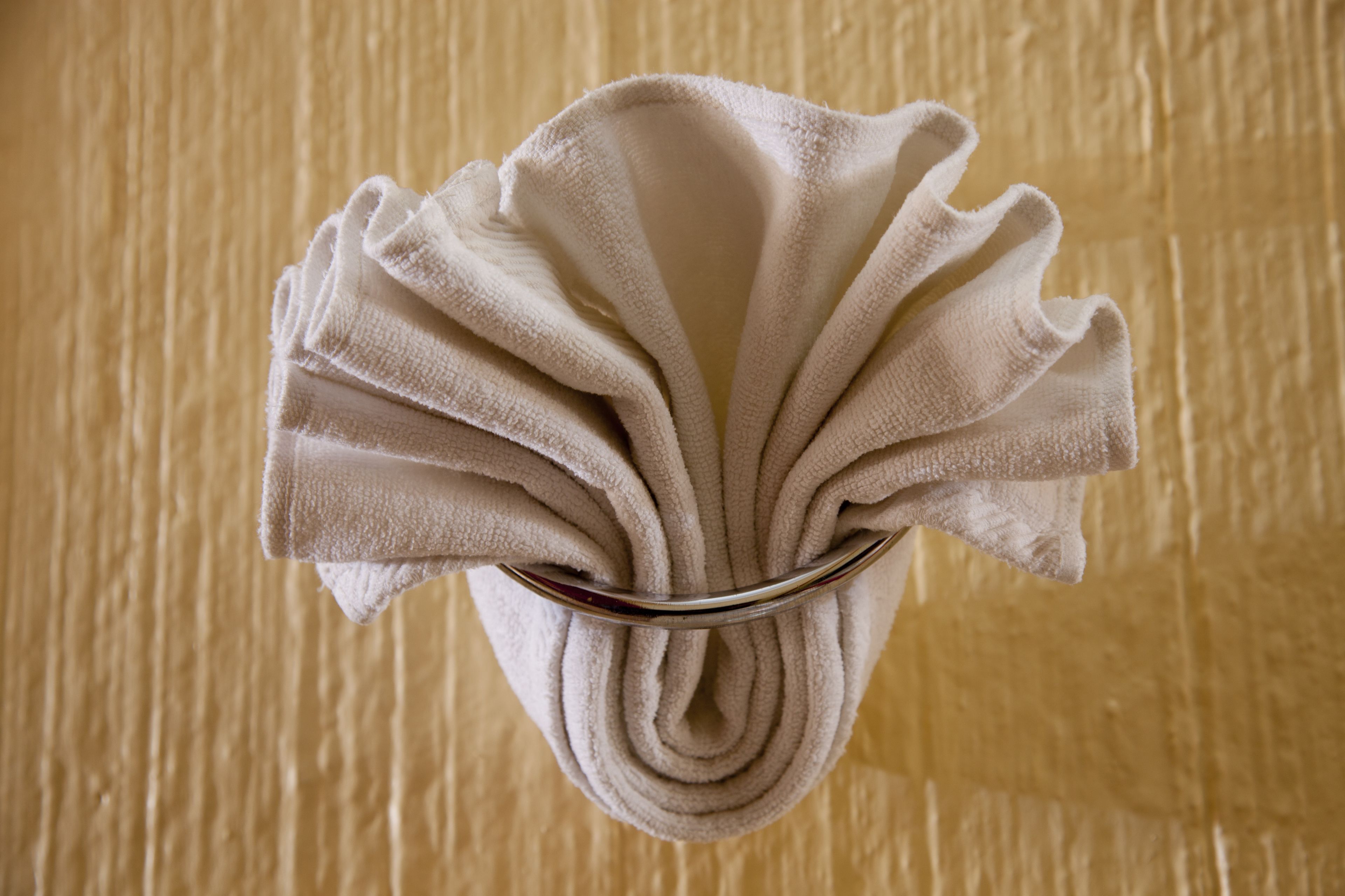 A towel folded in a unique, decorative manner, placed on a wooden surface.
